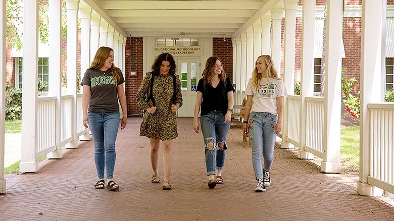 four students walking down an outside breezeway