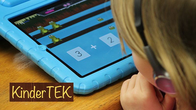 a young individual in ear phones looking at a KinderTEK book